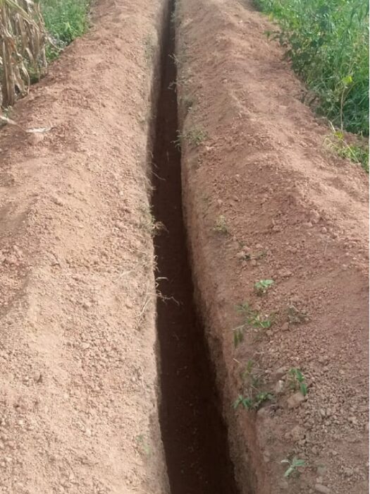 A long straight narrow trench dug through dry ground for an underground cable run