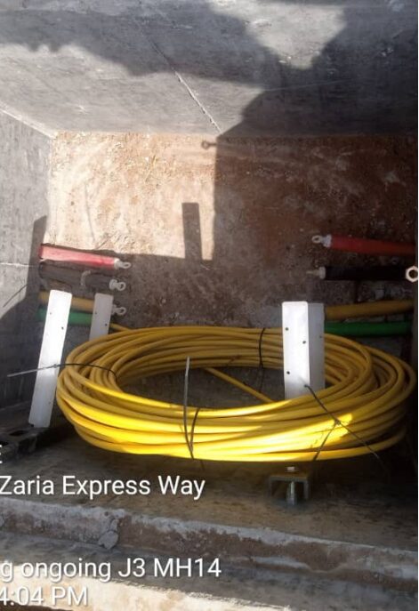 Interior of a concrete utility chamber on the Zaria Express Way with a coil of yellow cable lashed to brackets